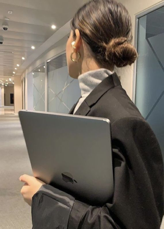 Femme avec un chignon et une veste de costume qui tiens un ordinateur portable