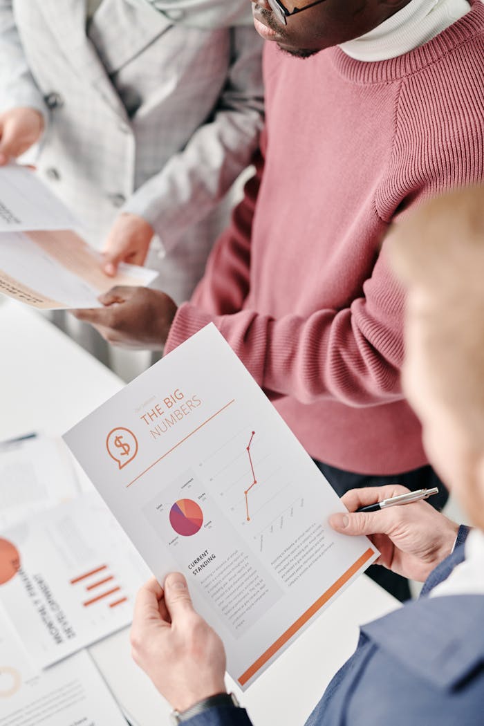 services-01 A group of professionals reviewing financial reports with graphs and statistics at a meeting.