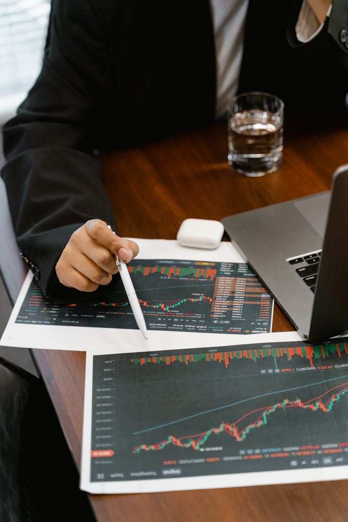 services-02 Close-up of a business analyst reviewing printed financial graphs and charts at an office desk.